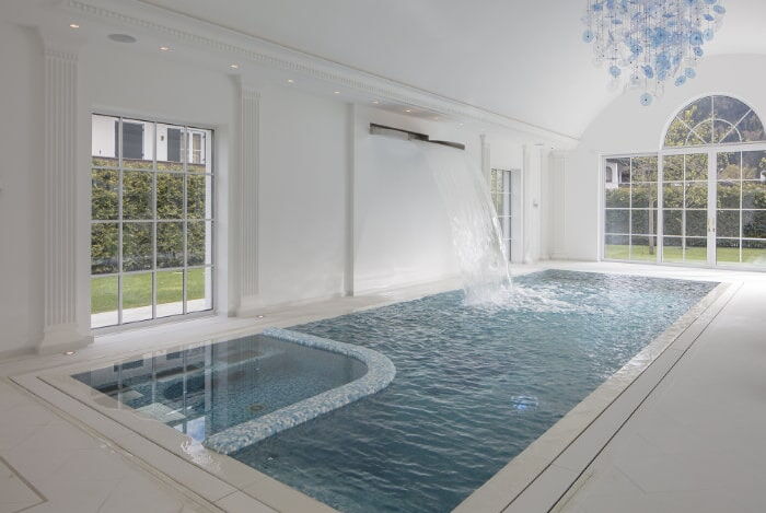 Mosaikgefliestes Betonschwimmbecken mit integriertem Whirlbereich und wandmontierter Schwallbrause