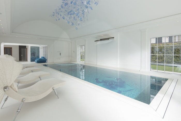 Mosaikgefliestes Betonschwimmbecken mit integriertem Whirlbereich und wandmontierter Schwallbrause