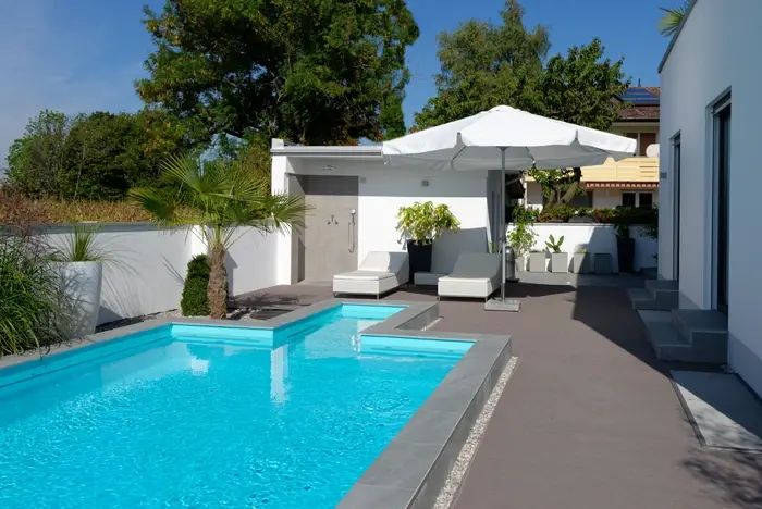 moderner Aussenpool mit Sonnenliegen und Sonnenschirm